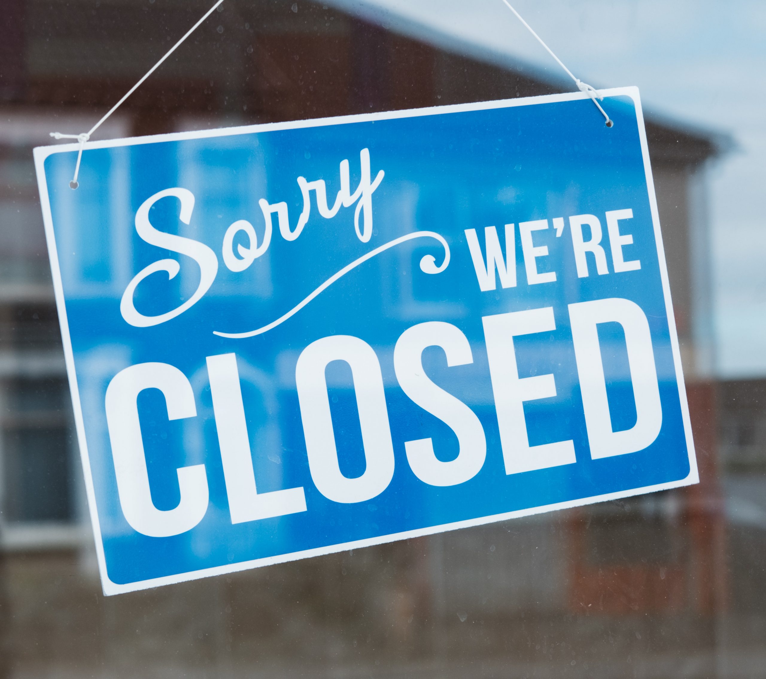 "Sorry We're Closed" sign hanging in window